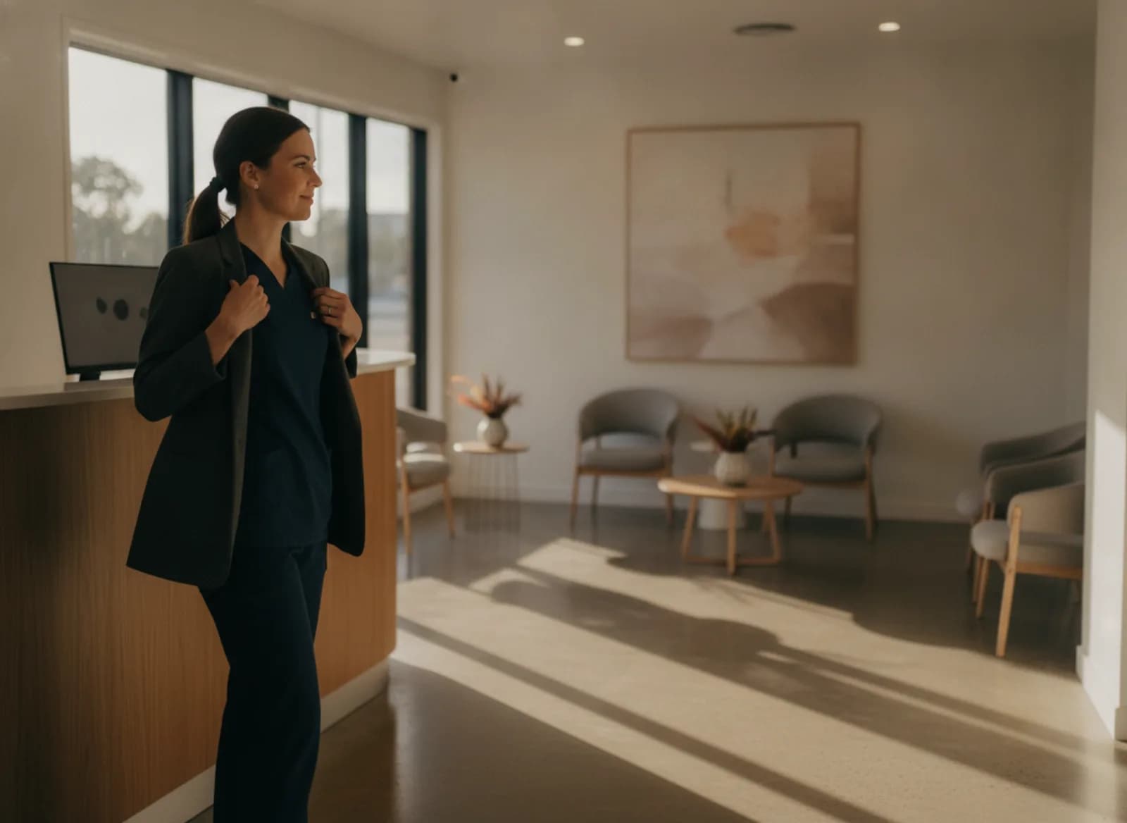 A receptionist at an empty clinic front desk at the end of the day