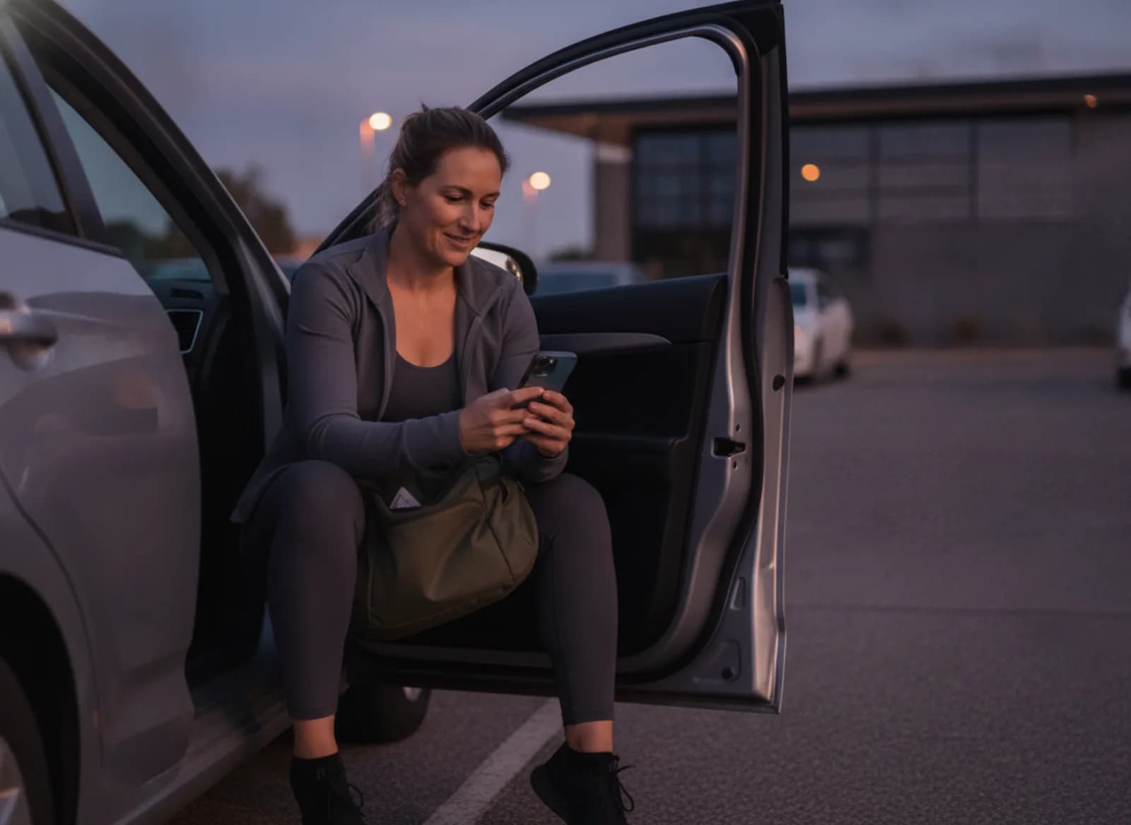 A member checking her phone in the car park before an early class