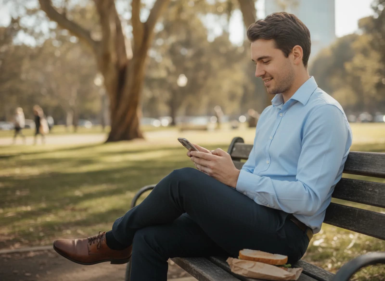 A young man on his lunch break reading a message on a park bench
